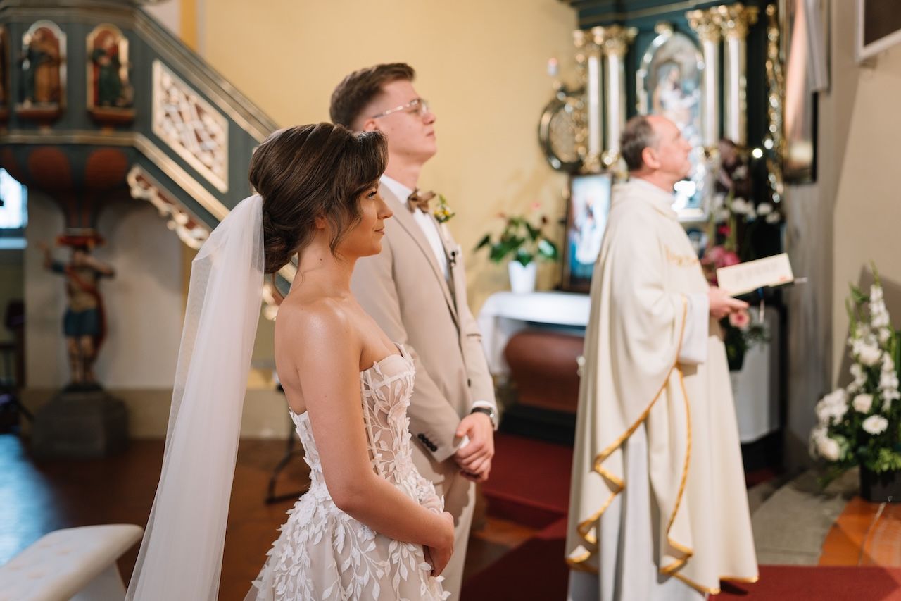 Bride and groom standing together at church altar during wedding ceremony with priest.