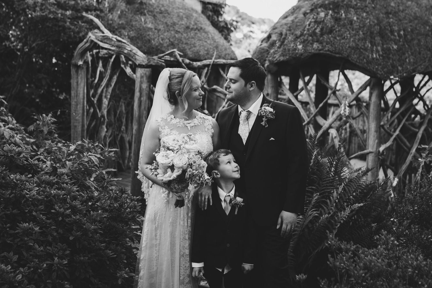 A wedding couple with their child in Furzey Gardens, natural family-focused wedding photography