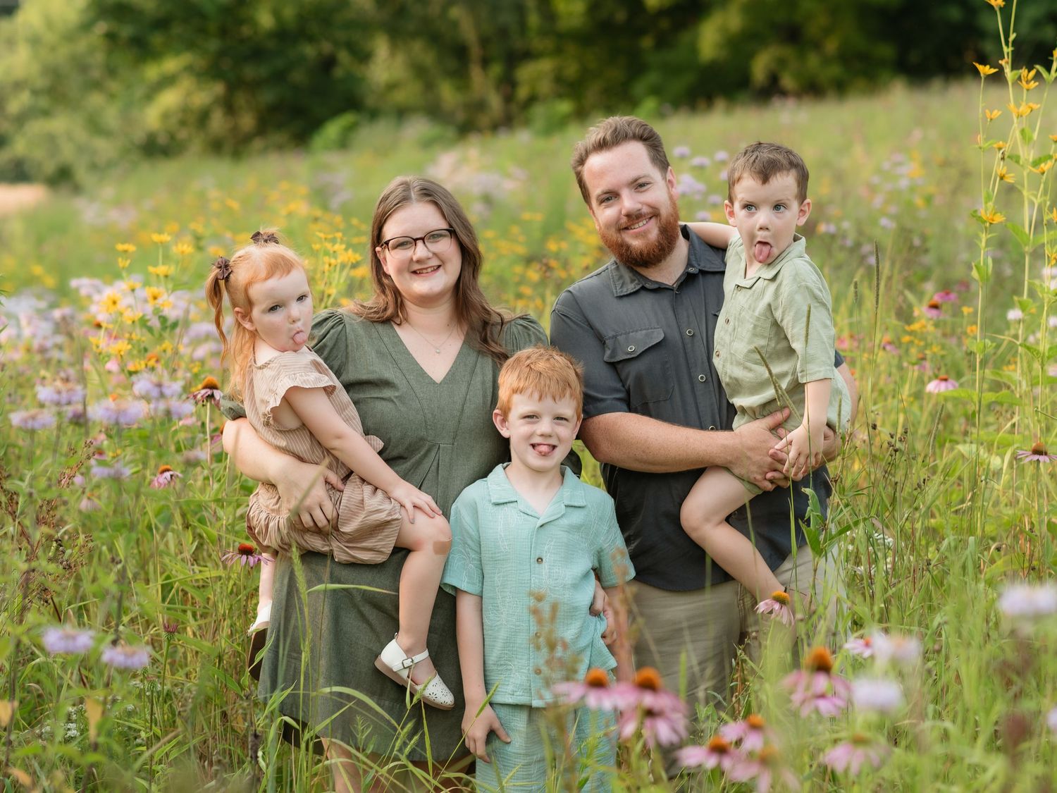 Family enjoying a picnic together in a wildflower meadow at sunset.