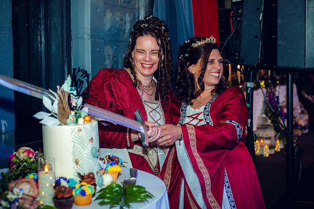People in red graduation robes celebrate with cake and smiles at a graduation ceremony.