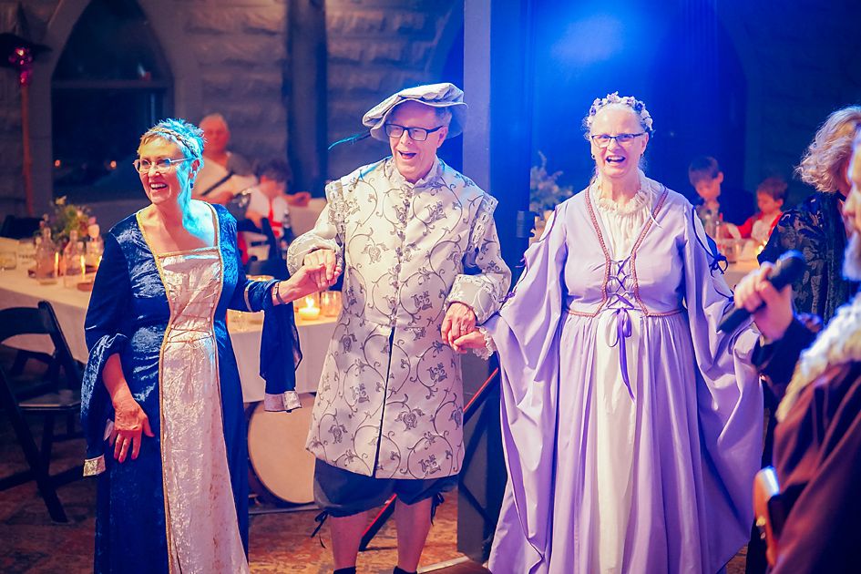 Wedding guests dancing together on a dimly lit dance floor with purple and blue lighting effects.