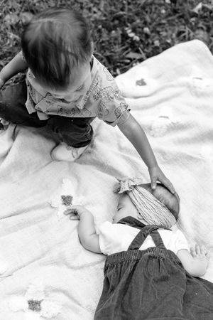 A series of black and white images showing a baby lying on a white blanket outdoors.