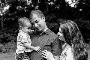 Black and white intimate family portrait captured outdoors with natural lighting.