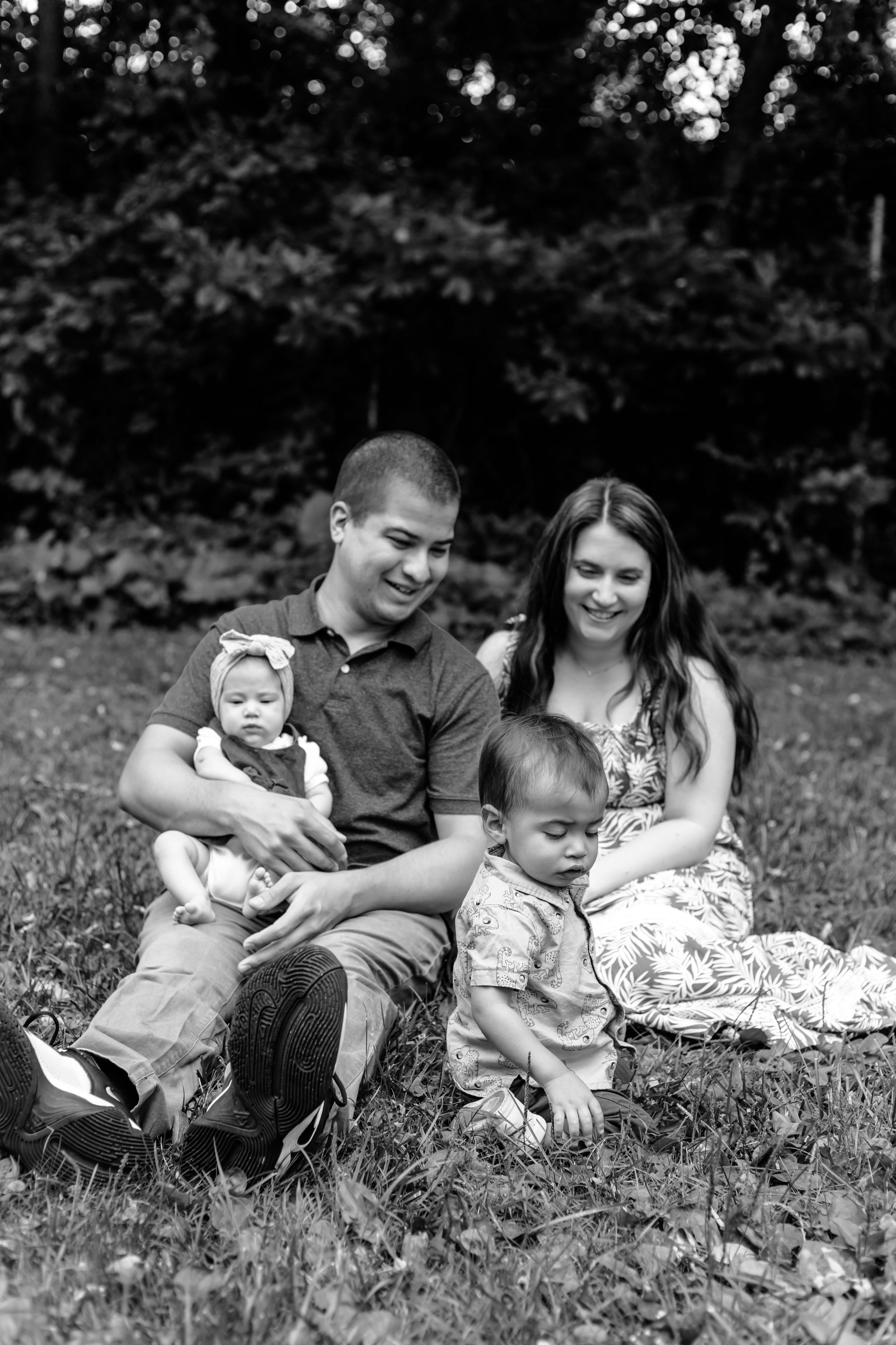Black and white series of a family relaxing together on grass during an outdoor photo session.
