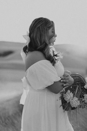 Black and white portrait of woman in off-shoulder dress holding flowers.