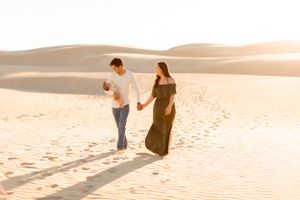 Couple strolls together across desert landscape at sunset.