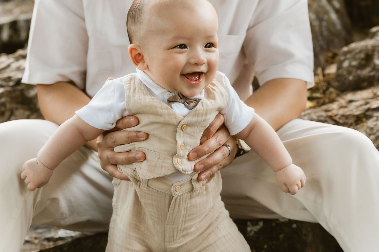 Baby laughing while being gently held upright by dad during Brisbane outdoor family shoot
