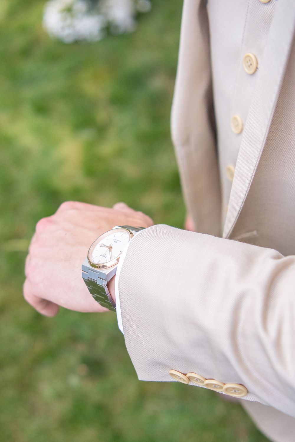 Close-up detail shot of gold buttons on a cream colored suit sleeve.