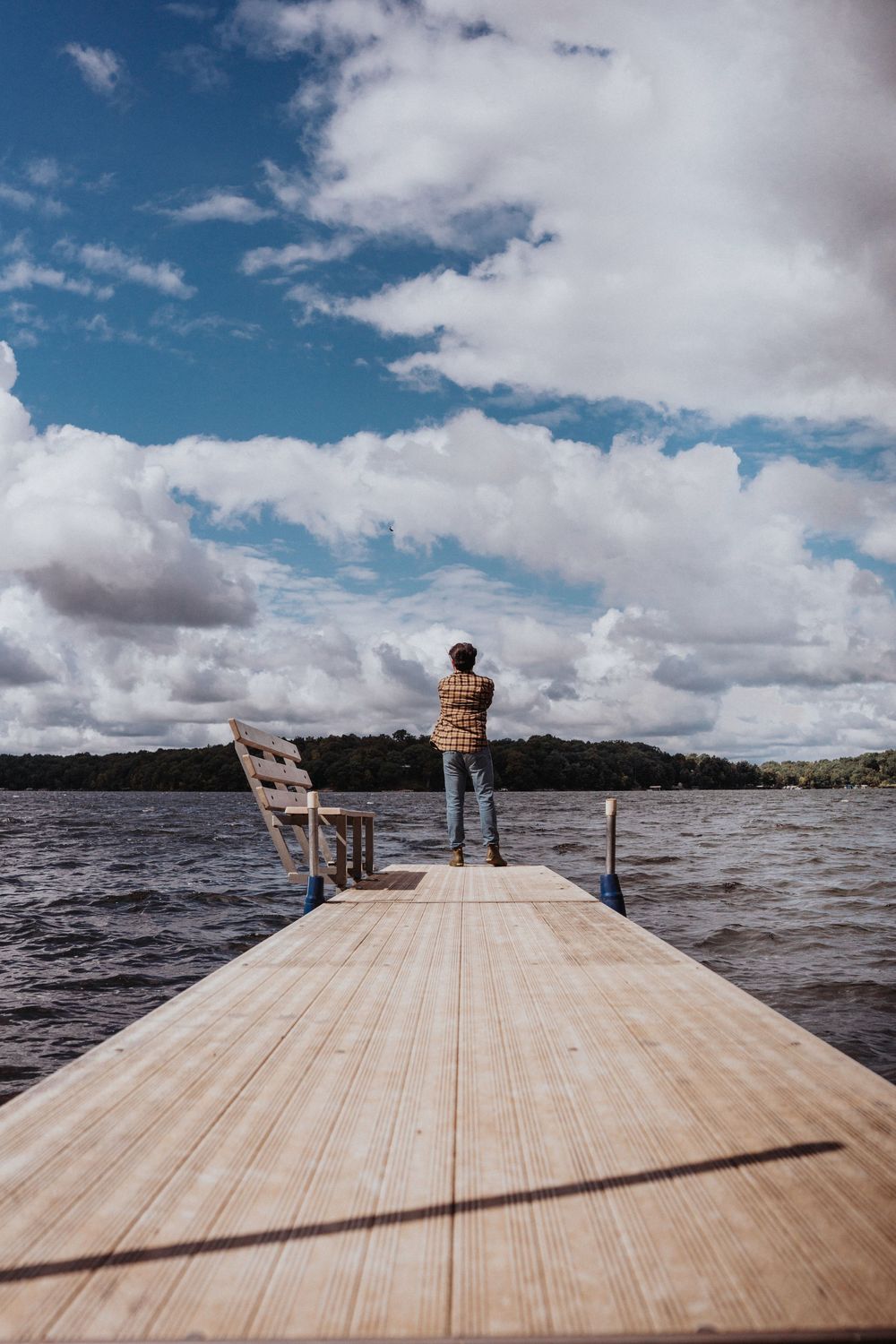 Wooden dock stretches out over choppy lake waters under dramatic cloudy sky.