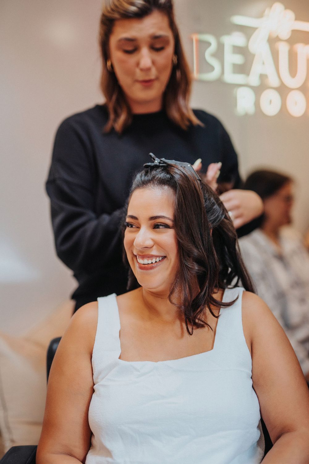 A person in white smiles joyfully during an indoor celebration.