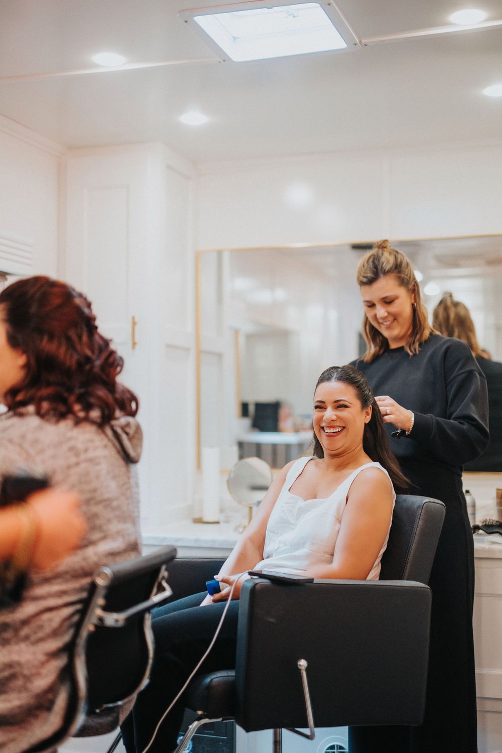A candid moment of laughter during wedding preparations at a brightly lit salon.