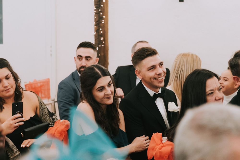 Wedding guests smile and laugh during a joyful celebration in an indoor venue.