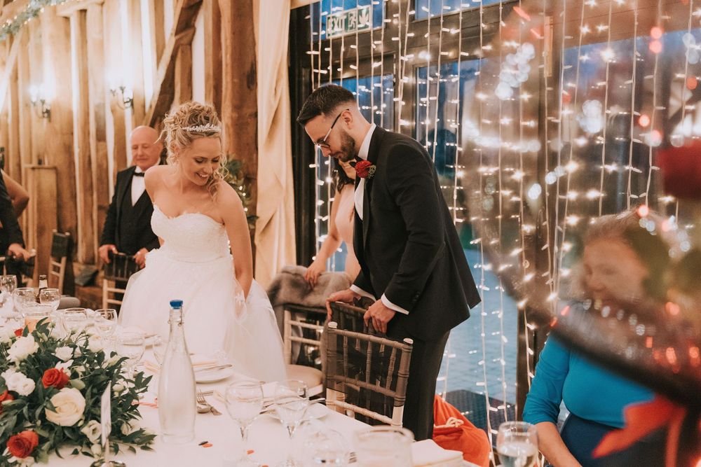 Wedding guests celebrate at a rustic venue decorated with twinkling fairy lights and holiday decor.