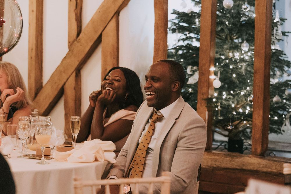 Wedding guests seated at long tables in a rustic wooden barn venue during reception.