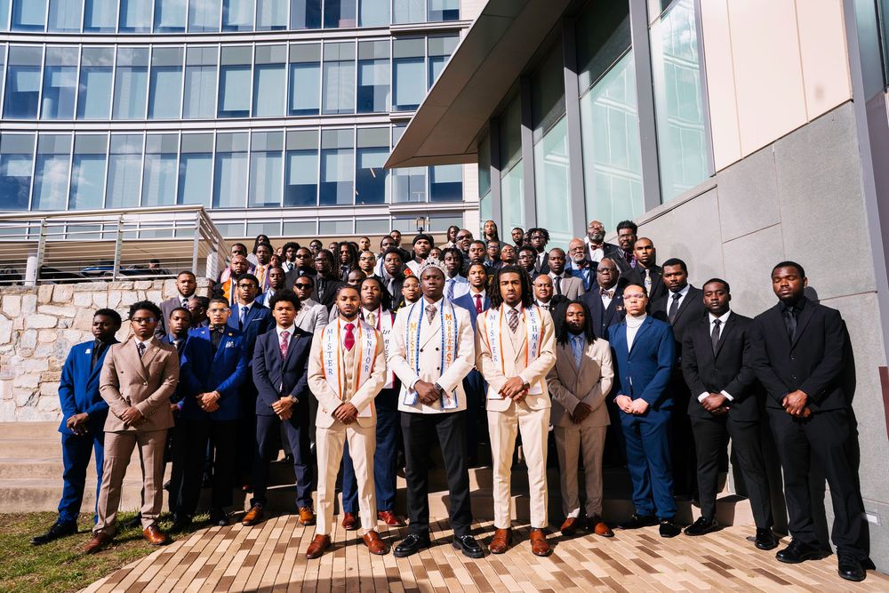 Large group of business professionals gathered outside a modern office building for a group photo.