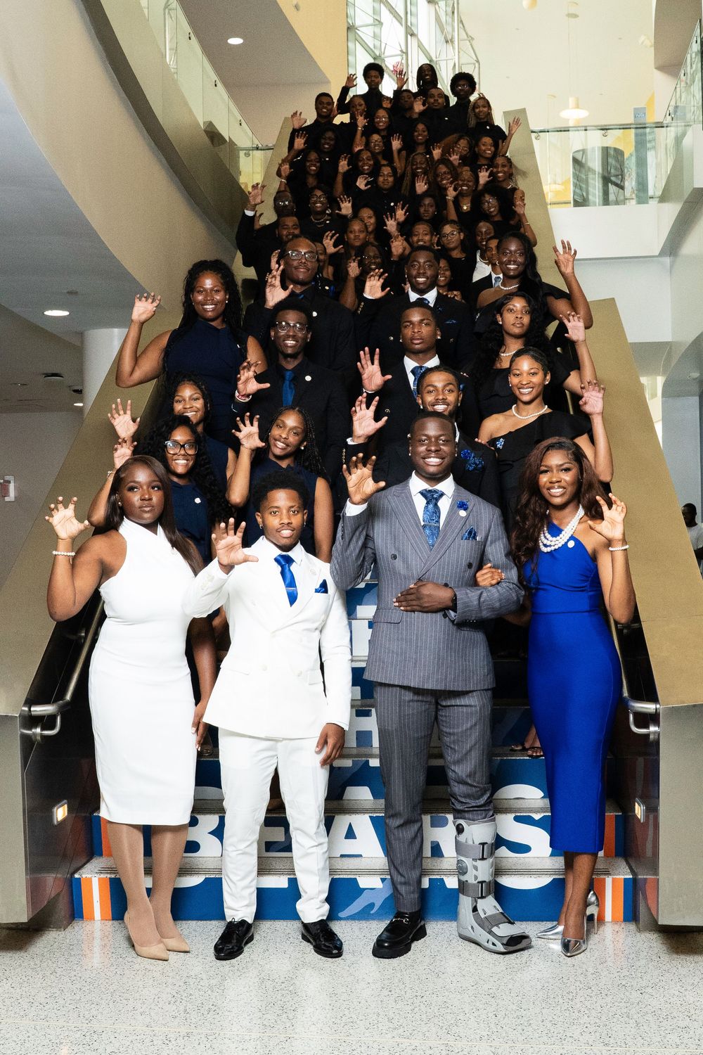 A sequence of five photos showing a group in formal attire posing and waving together in an indoor setting.