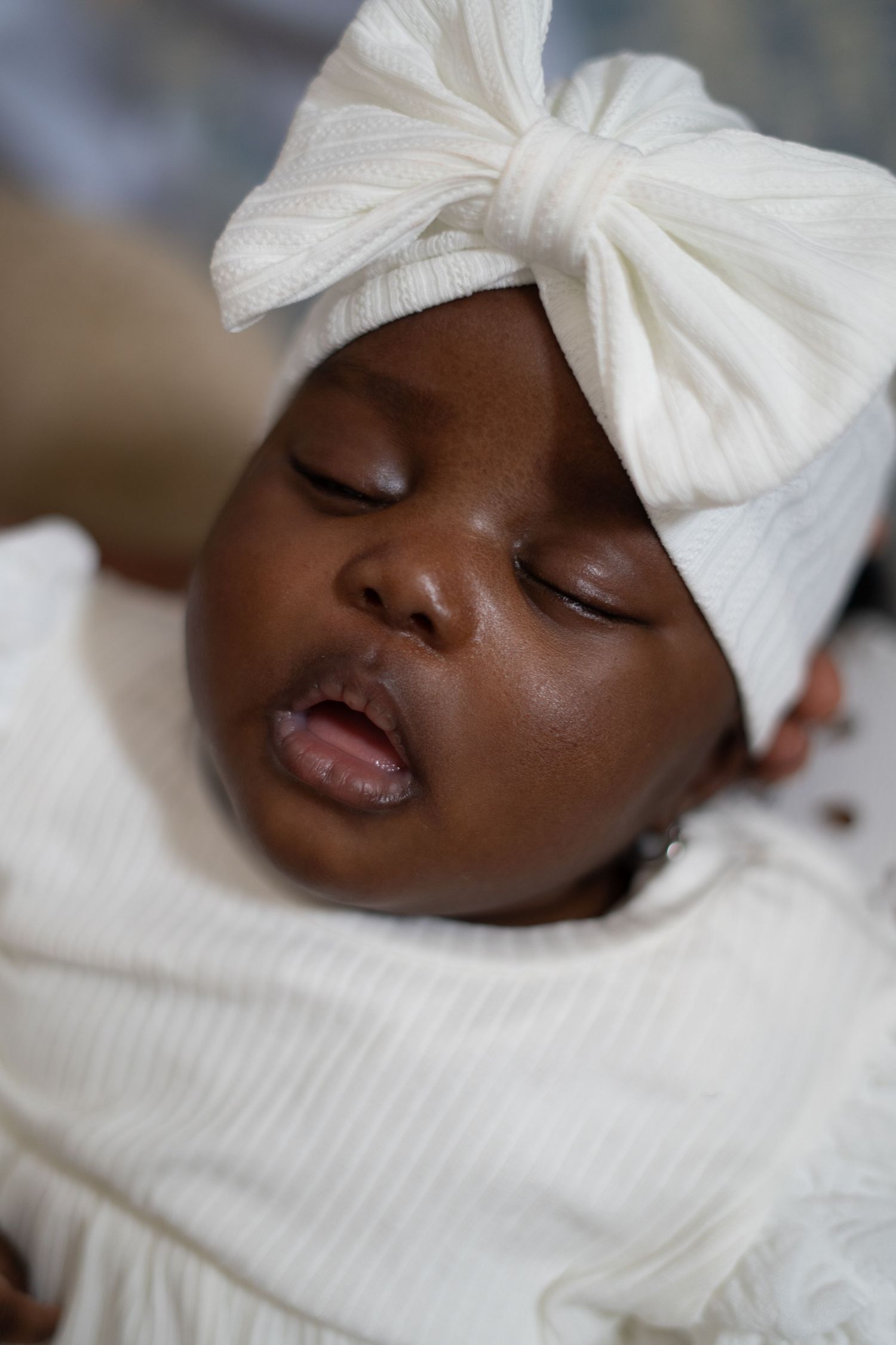 A baby wearing white baptismal dress and bonnet smiles joyfully in a series of candid portraits.
