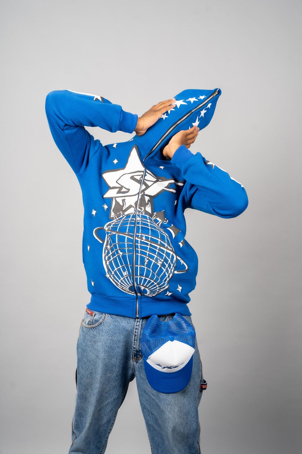Person wearing bright blue sweatshirt and jeans showing different poses against gray backdrop.