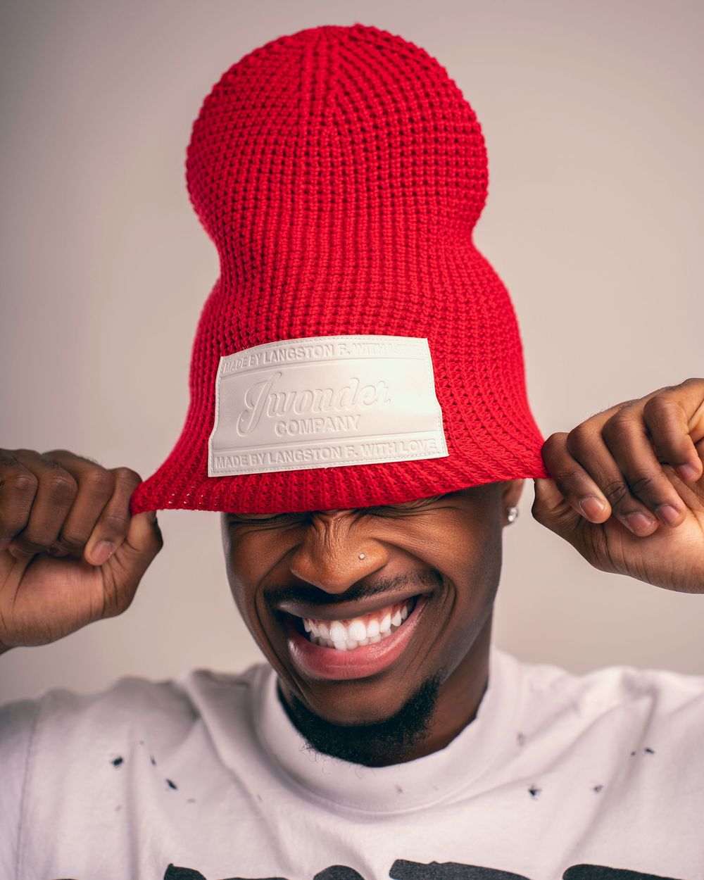Person wearing a bright red knit beanie making playful expressions in a sequence of photos.