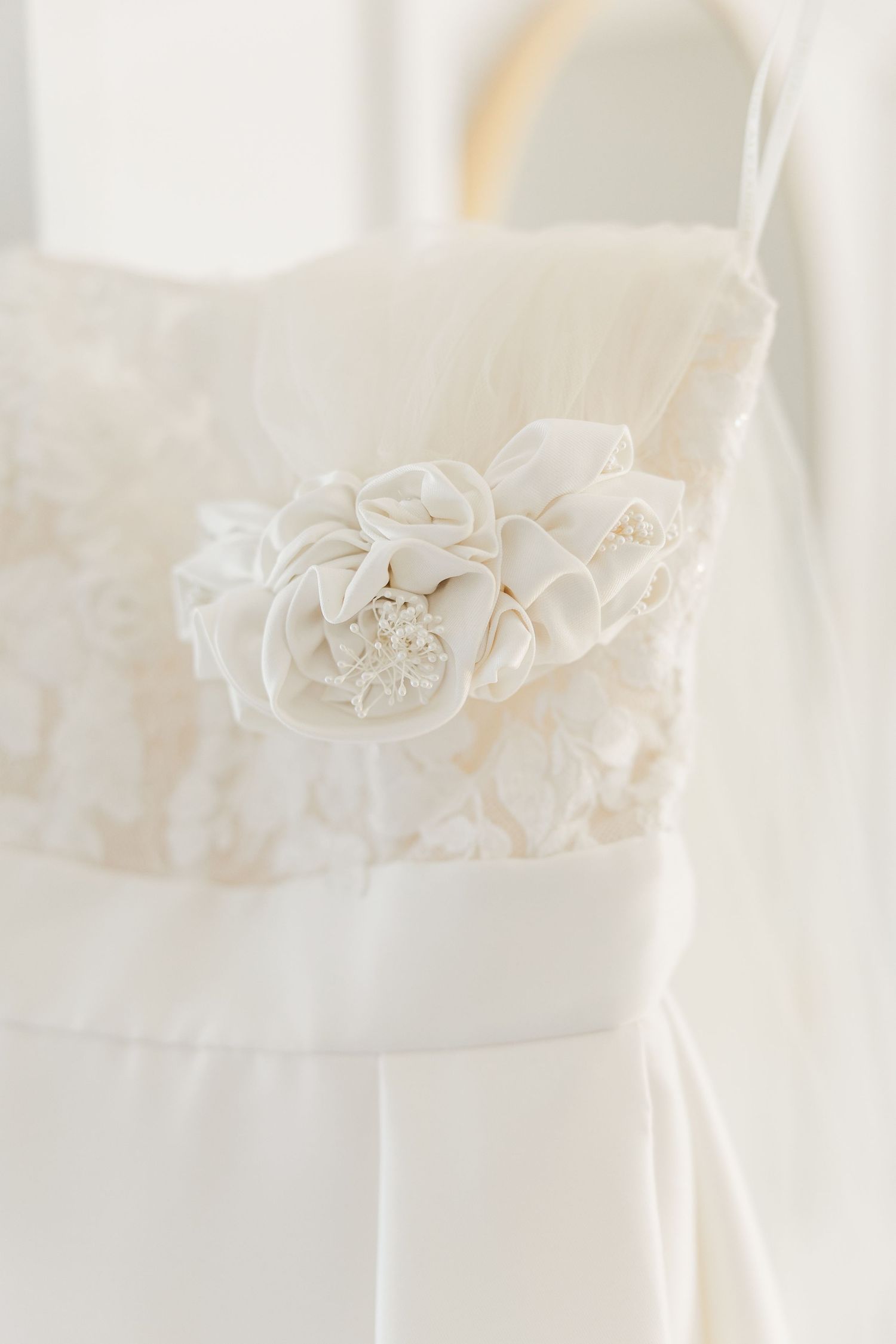 Close up detail of white wedding dress showing intricate lace and beading.