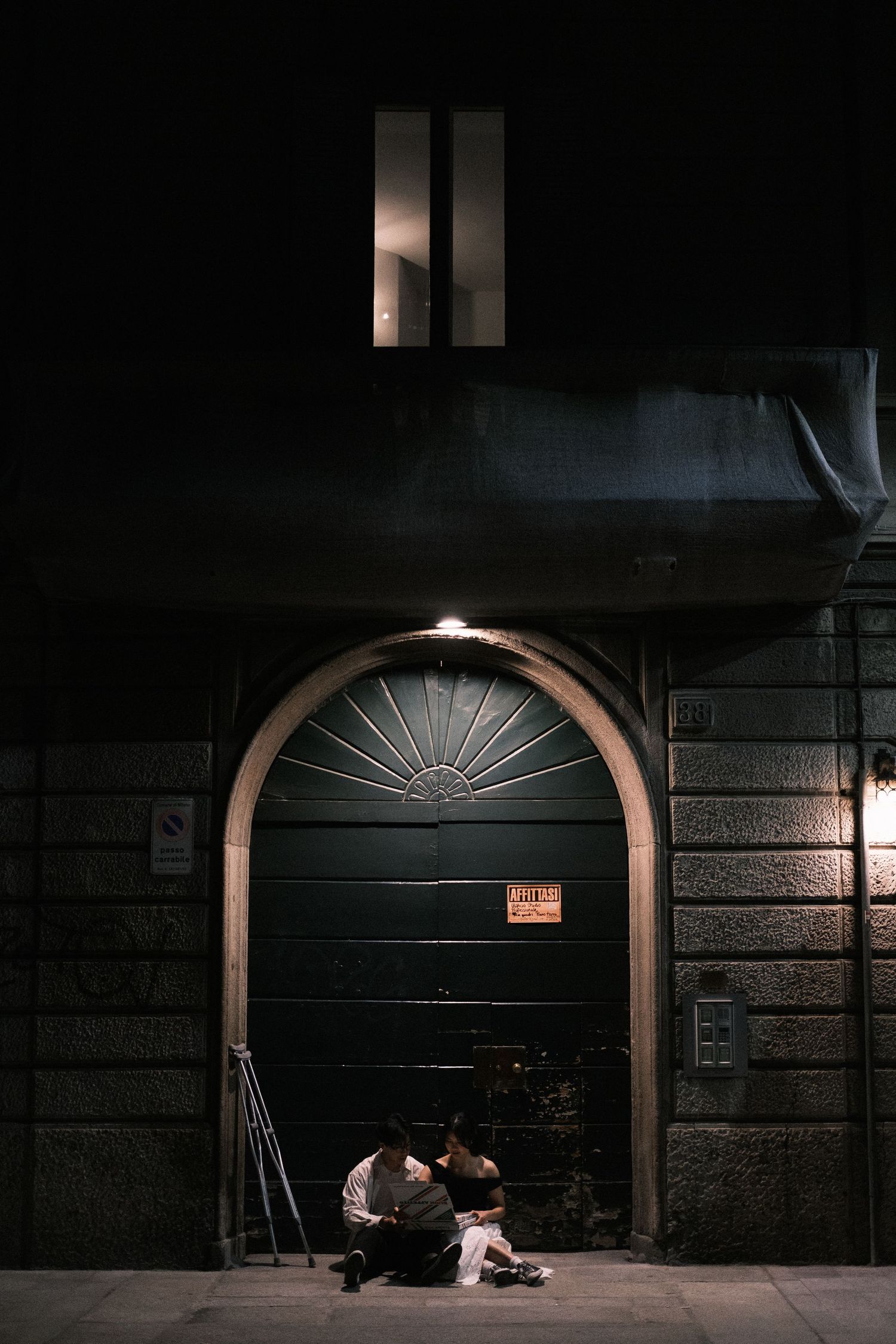 Dark urban doorways with arched entrances and dramatic lighting create a moody nighttime scene on a city street.