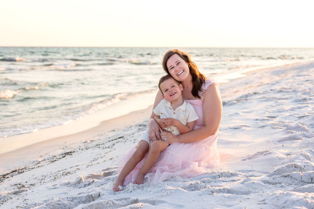 A family enjoying a sunset beach photoshoot together in matching white outfits along the shoreline.