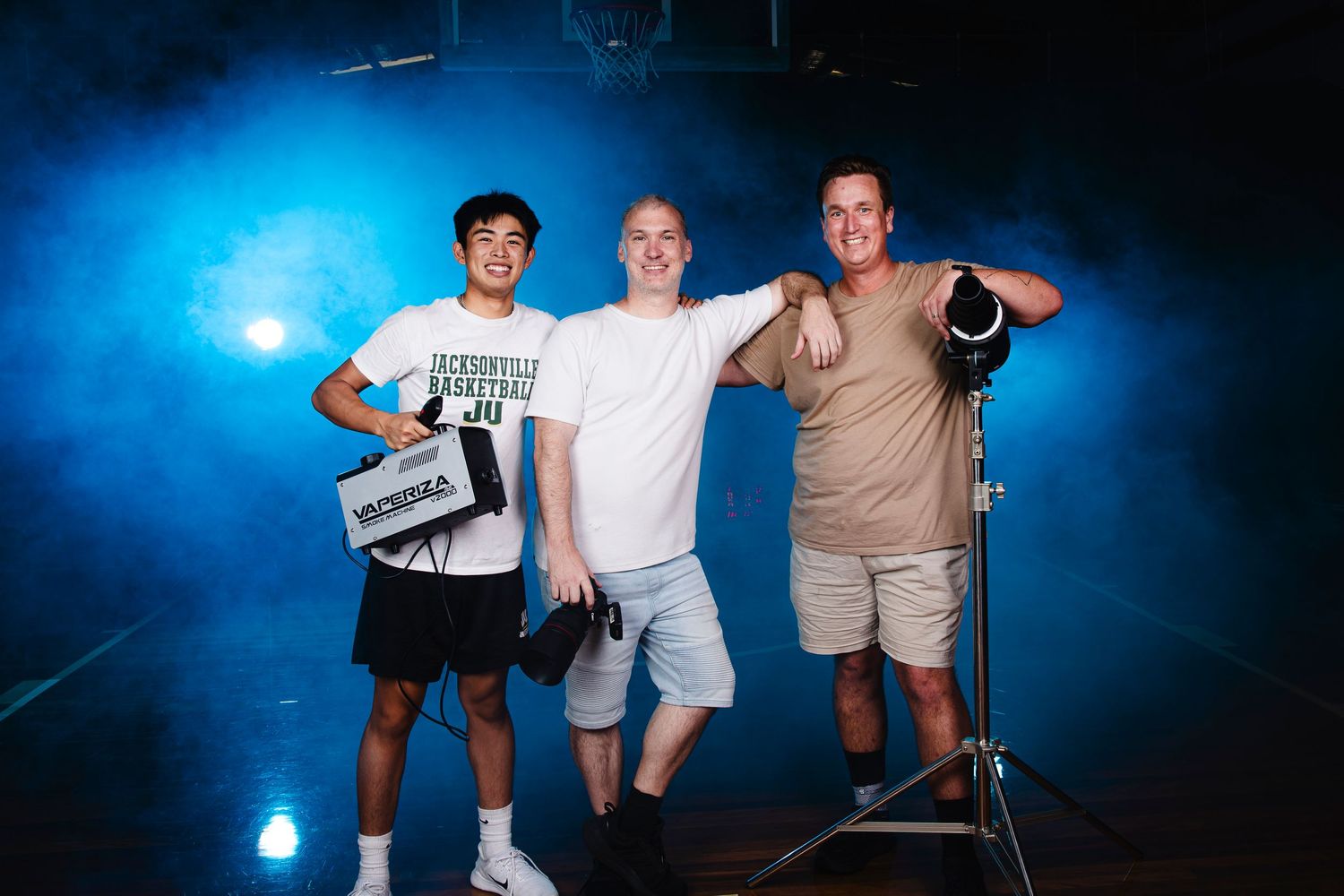 Group photo shoot in studio with dramatic blue lighting and professional camera equipment.