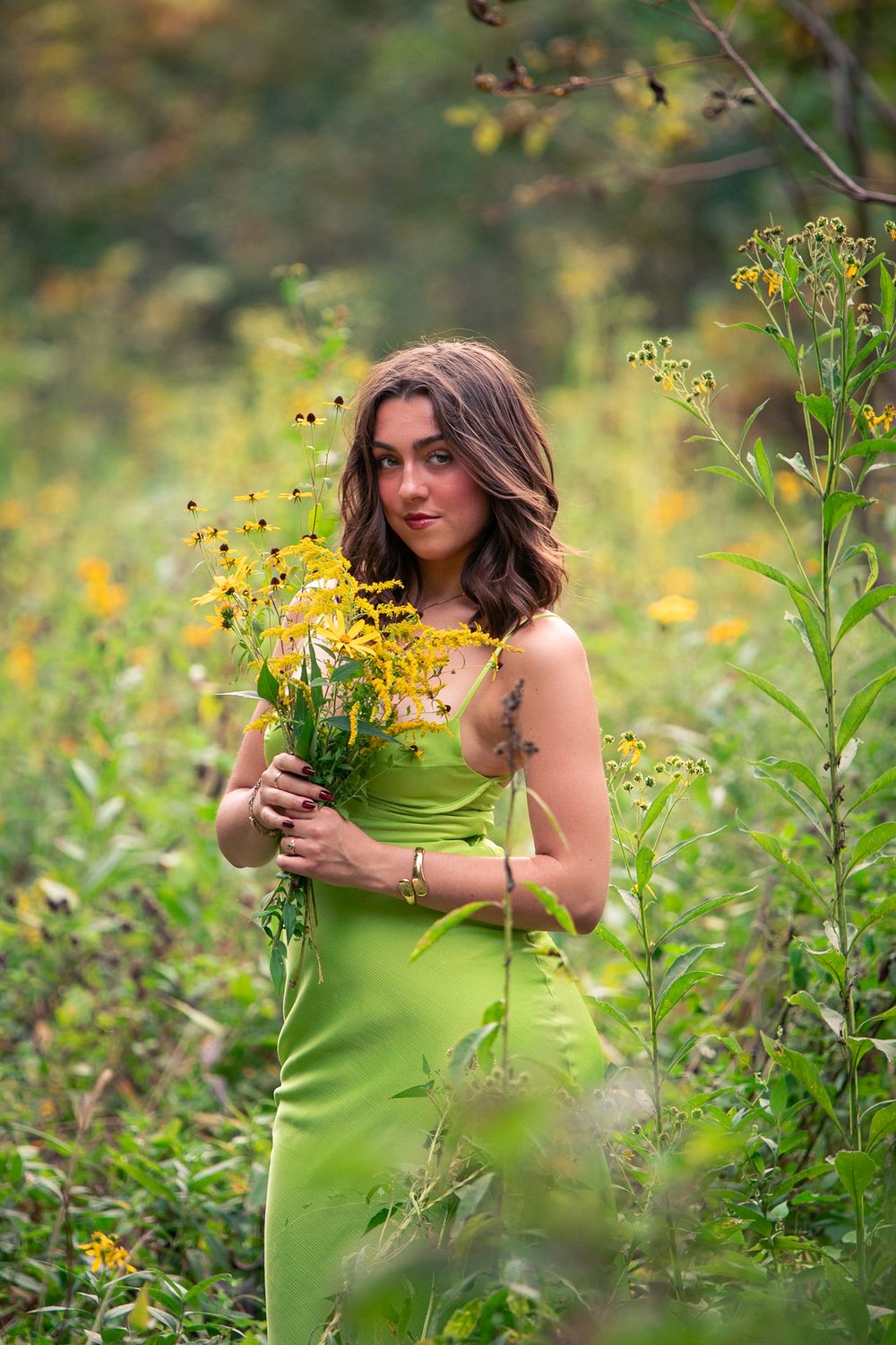 Senior in lime green dress posing among yellow wildflowers during a Columbia, Missouri portrait session.