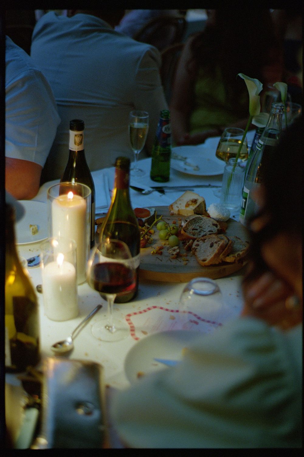 A sequence of candlelit table settings showing a dimly lit dinner scene with wine bottles and glassware.