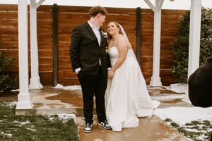 Bride and groom share a romantic moment outdoors in winter, with snow on the ground at their wedding venue.