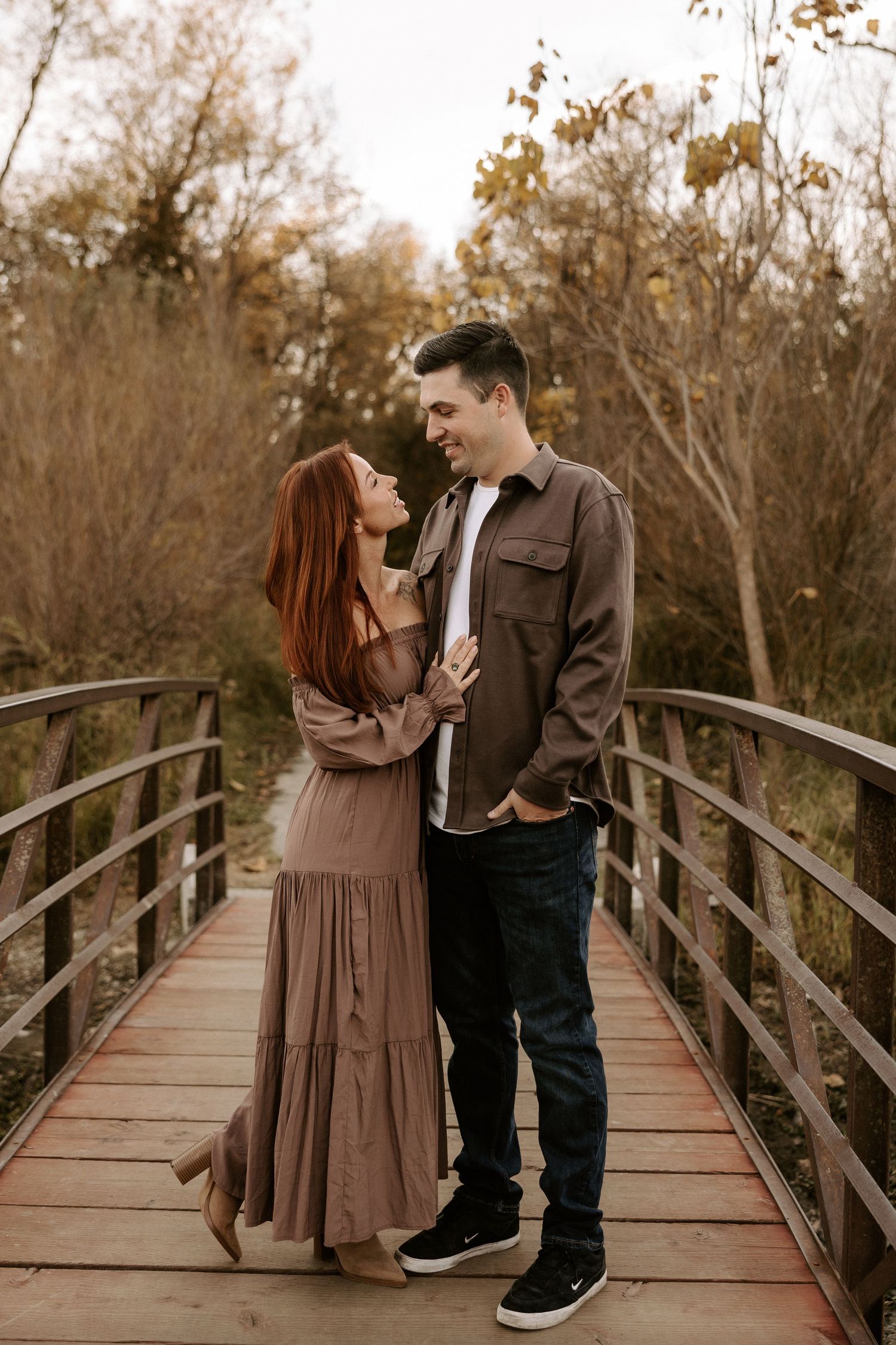 A couple shares romantic moments on a wooden bridge surrounded by autumn trees in a series of connected photos.