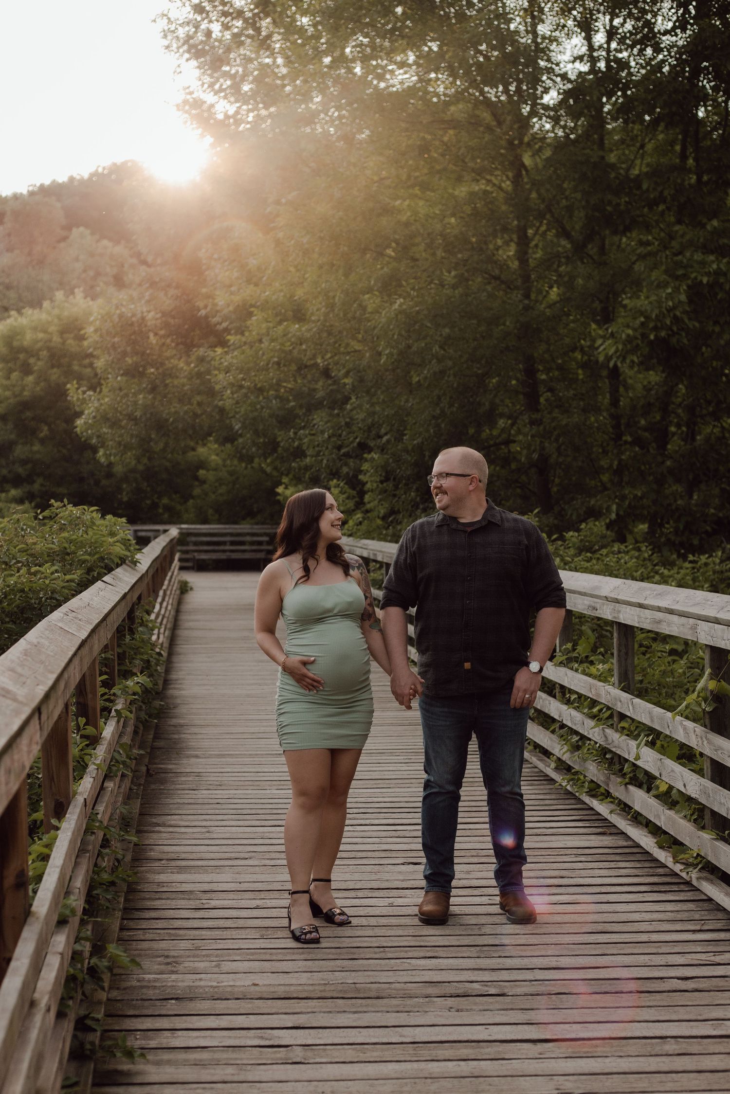 Couple takes a walk during sun set on a boardwalk in Burlington, Ontario for their maternity session.