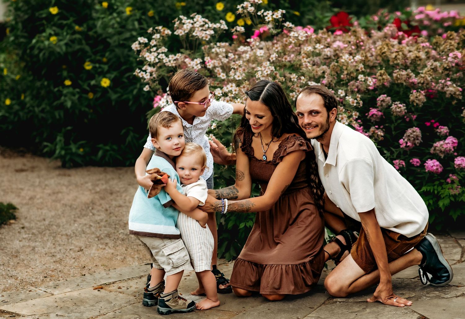 Family sitting together in a blooming garden with pink roses and greenery in the background.