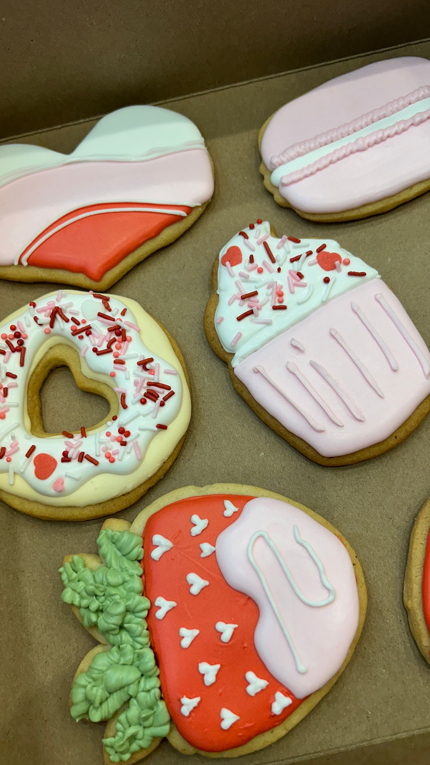 Decorated sugar cookies with strawberry and donut designs featuring red, pink, mint green, and white royal icing.