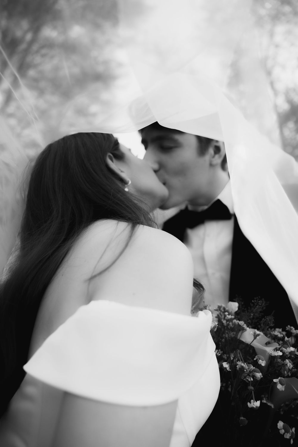 A romantic black and white wedding photo sequence showing a couple kissing while holding a bouquet of flowers.