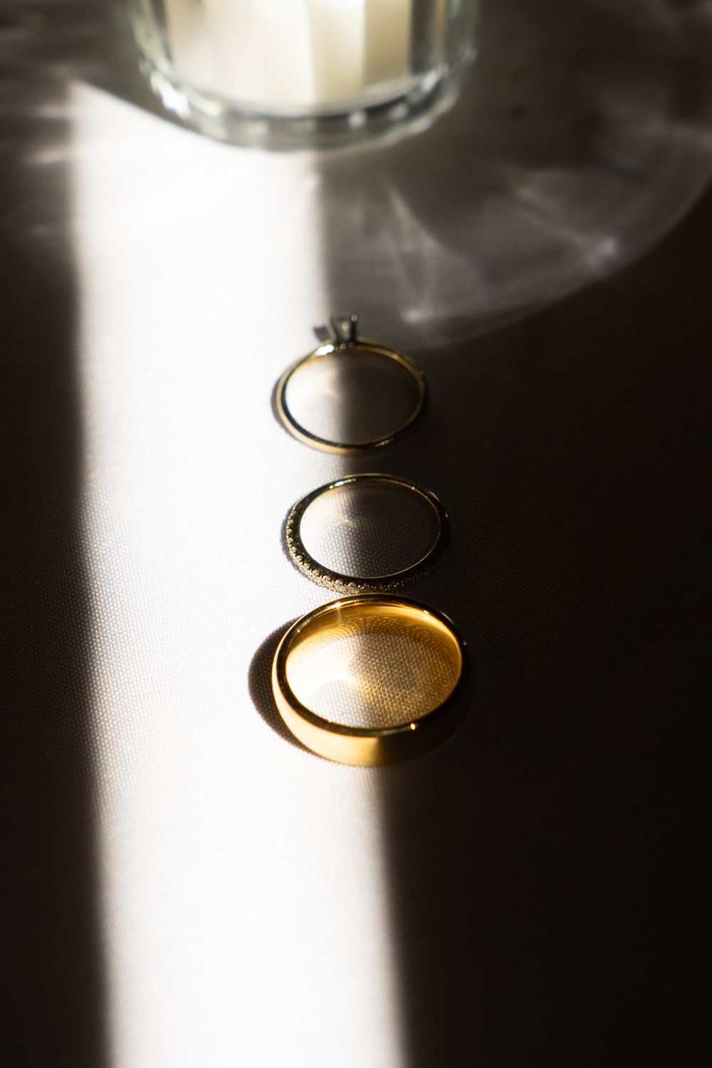 A sequence of artistic photos showing a wedding ring casting dramatic shadows in bright lighting against a white background.