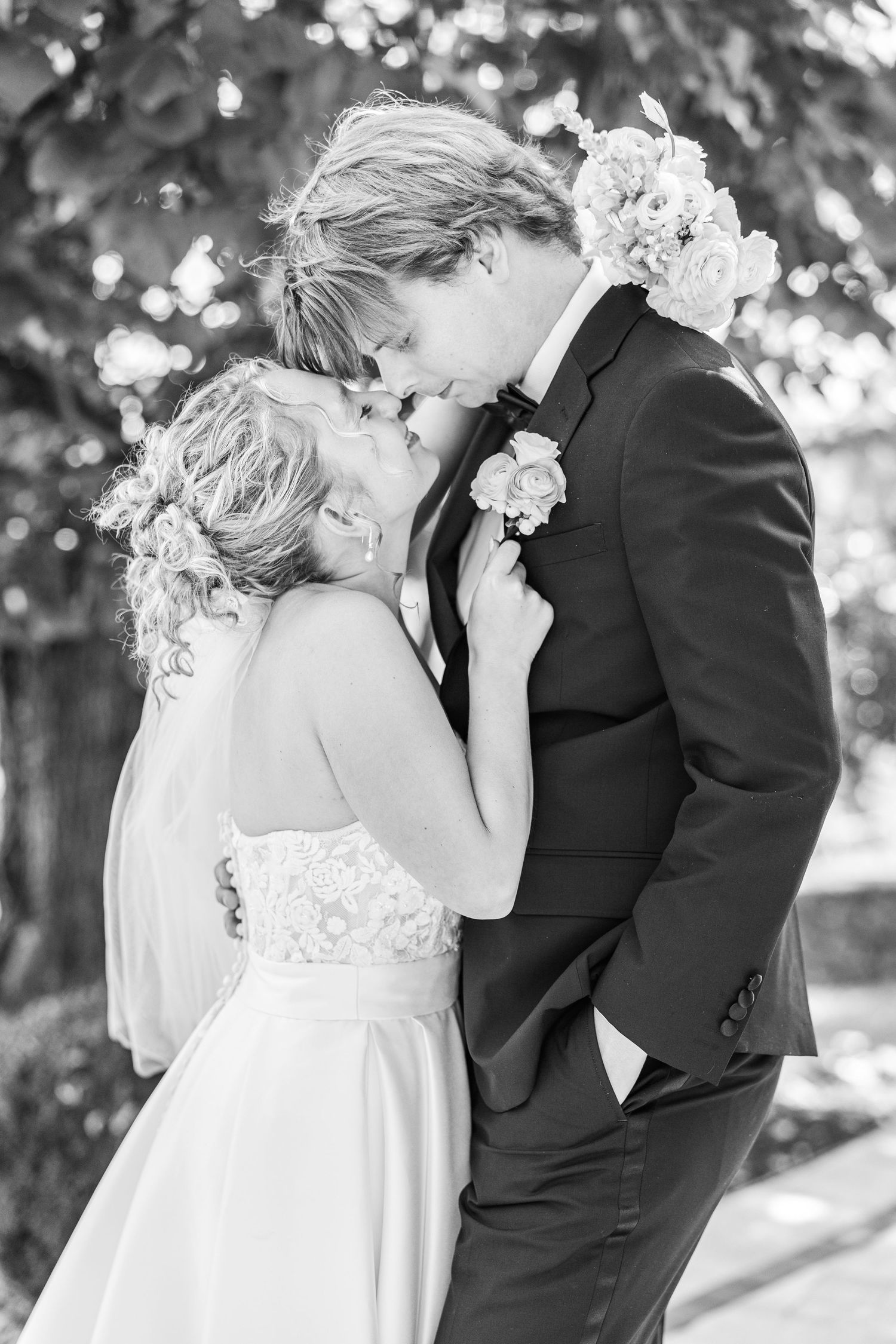 A black and white romantic wedding portrait showing a tender moment between newlyweds.