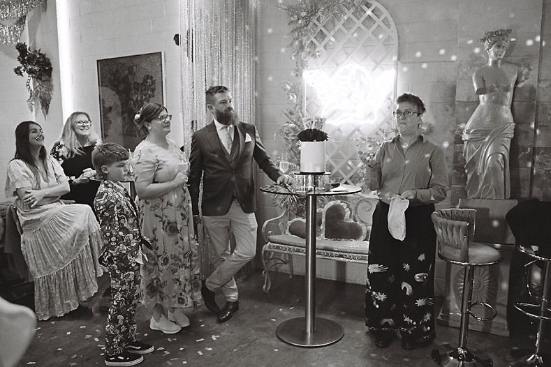 A panoramic black and white photo montage showing a wedding reception with guests mingling and celebrating.