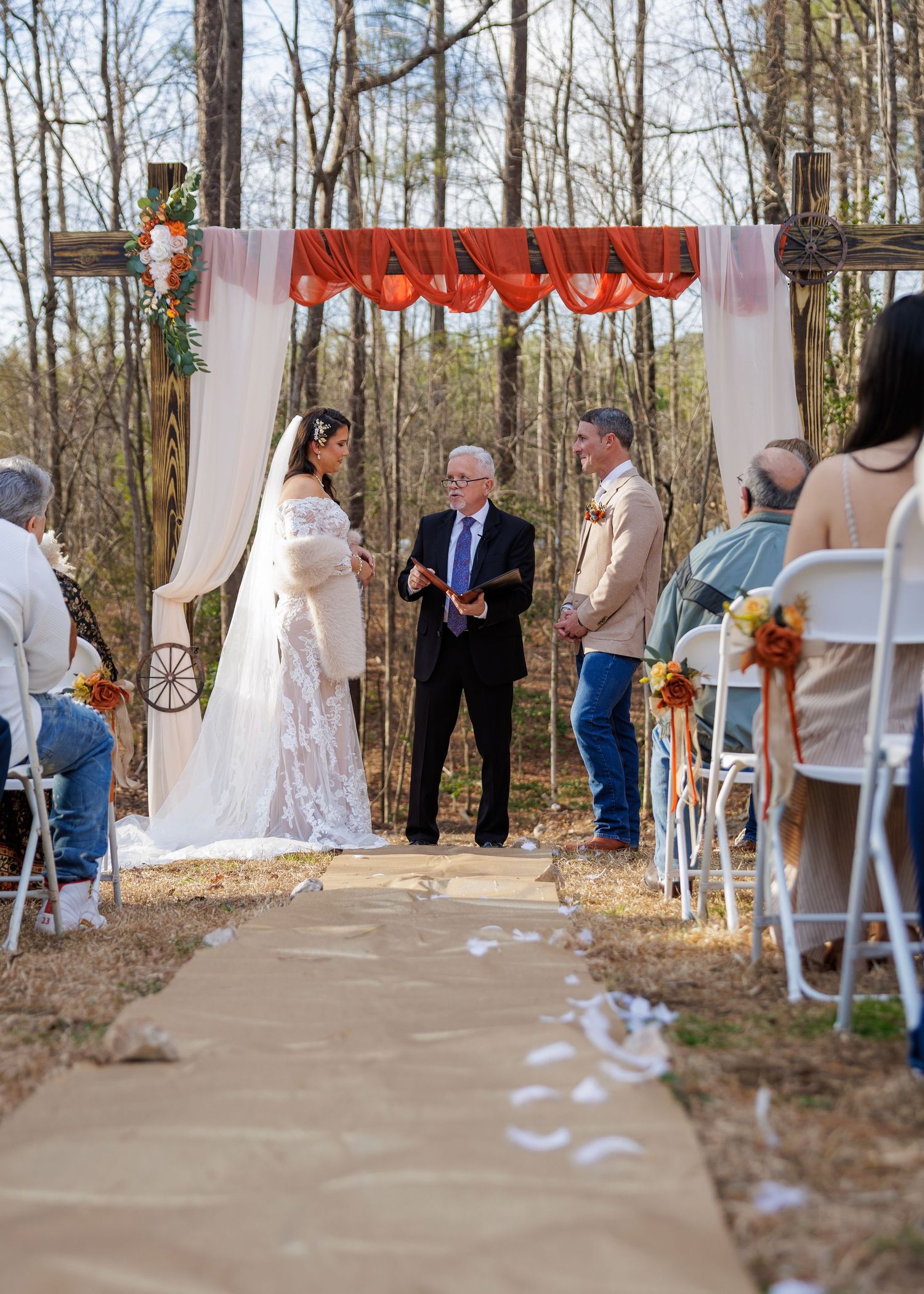 A romantic wedding ceremony under a floral arch with white roses as the newlyweds share their first kiss.