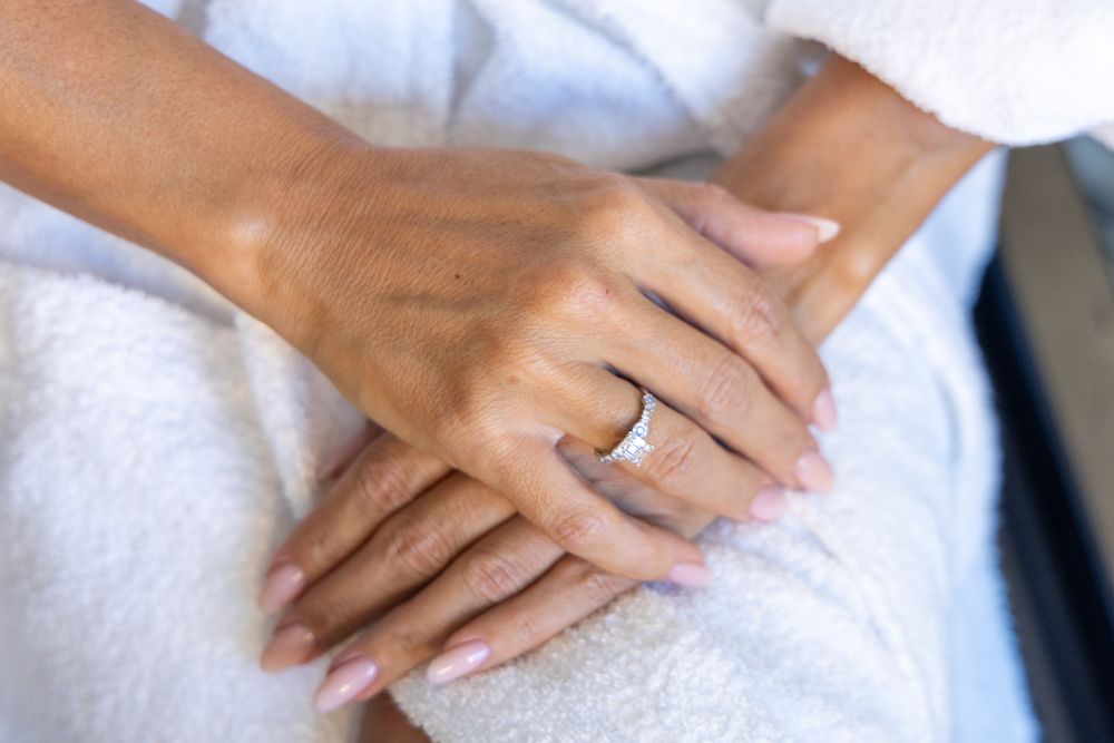 Close-up of hands with wedding ring resting on white fabric.