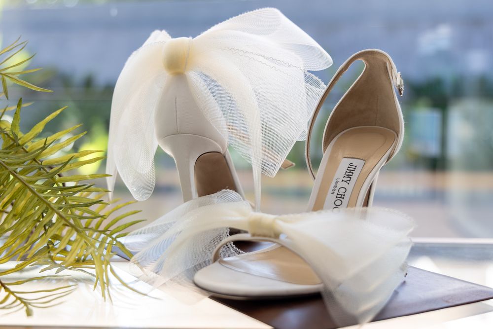 Elegant white wedding shoes with bow details photographed with natural light.
