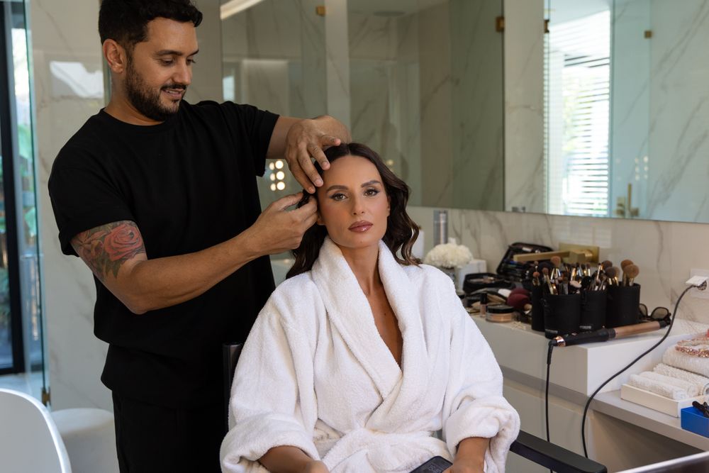 Professional hairstylist working on model's hair in makeup chair.