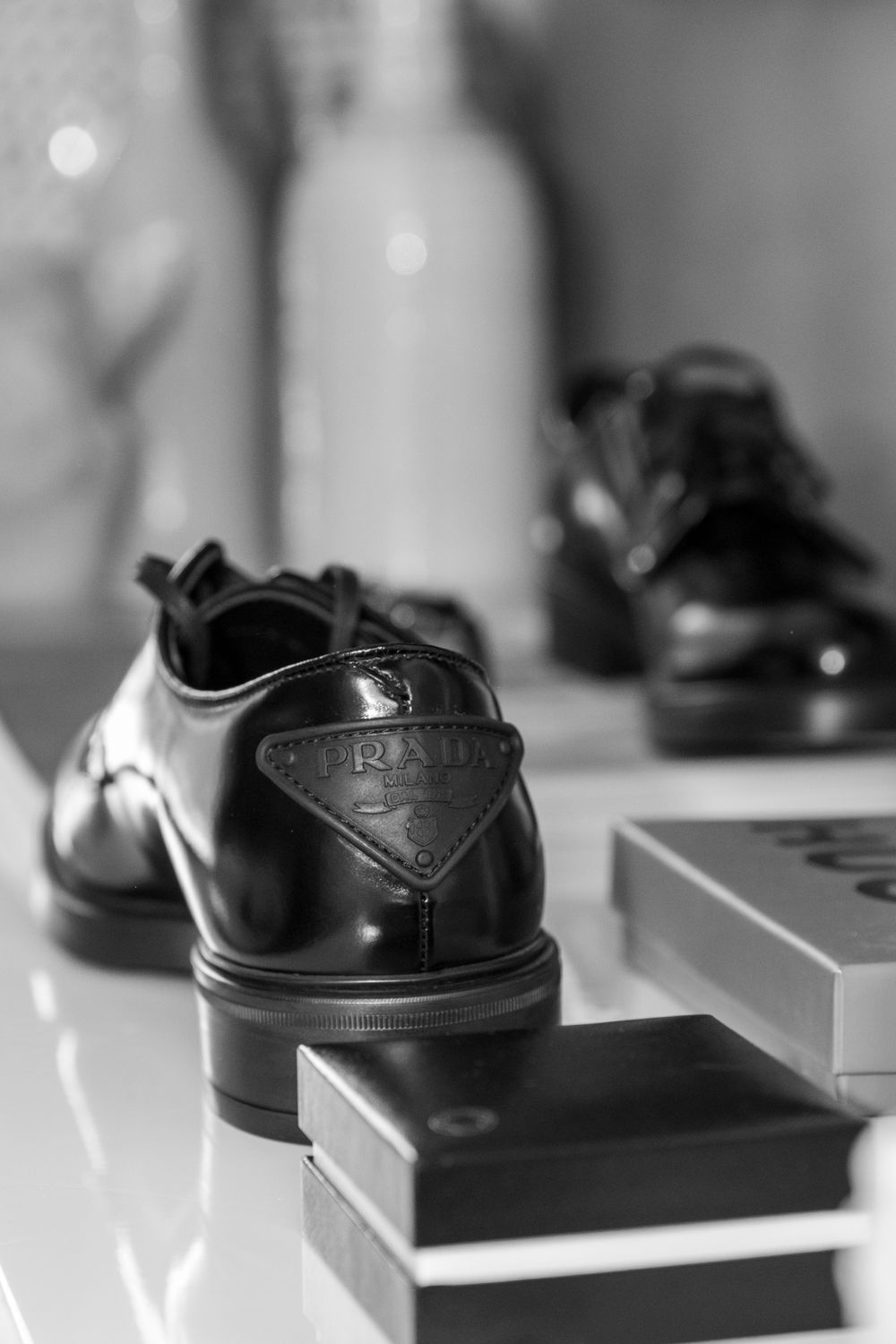 Close-up of black formal leather dress shoes on white surface with boxes.