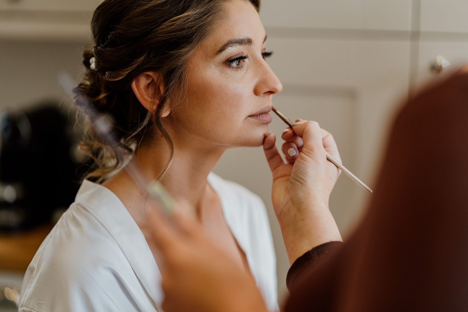 Close-up shots of bridal makeup application in natural window light.