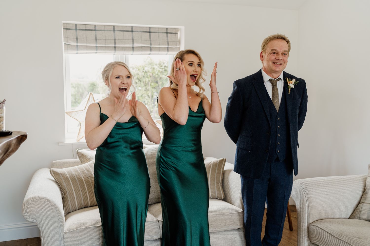 Wedding party members celebrate with joyful reactions and laughter in an indoor setting.