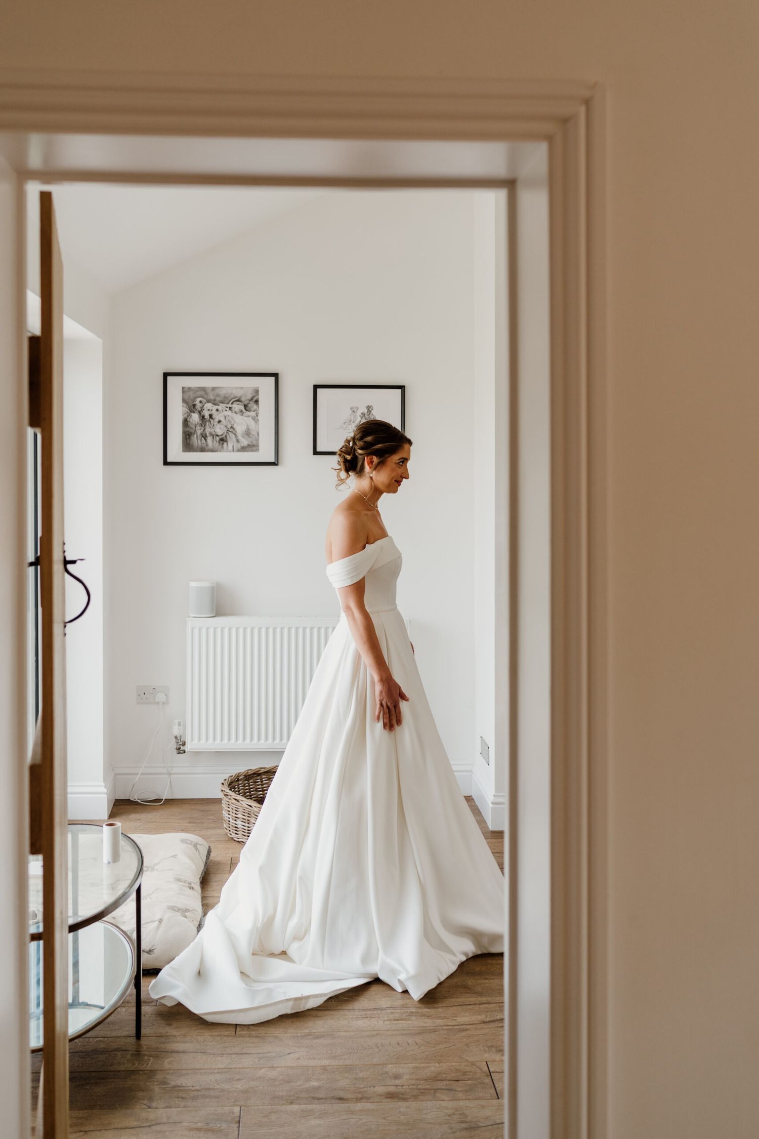 Elegant white wedding dress with flowing train photographed through doorways in natural light.