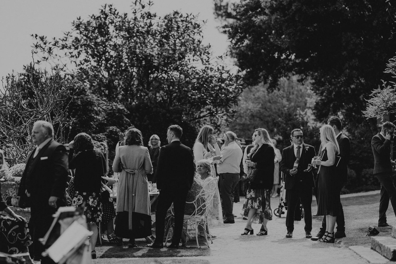 Black and white photo of wedding guests gathered outdoors for a celebration.