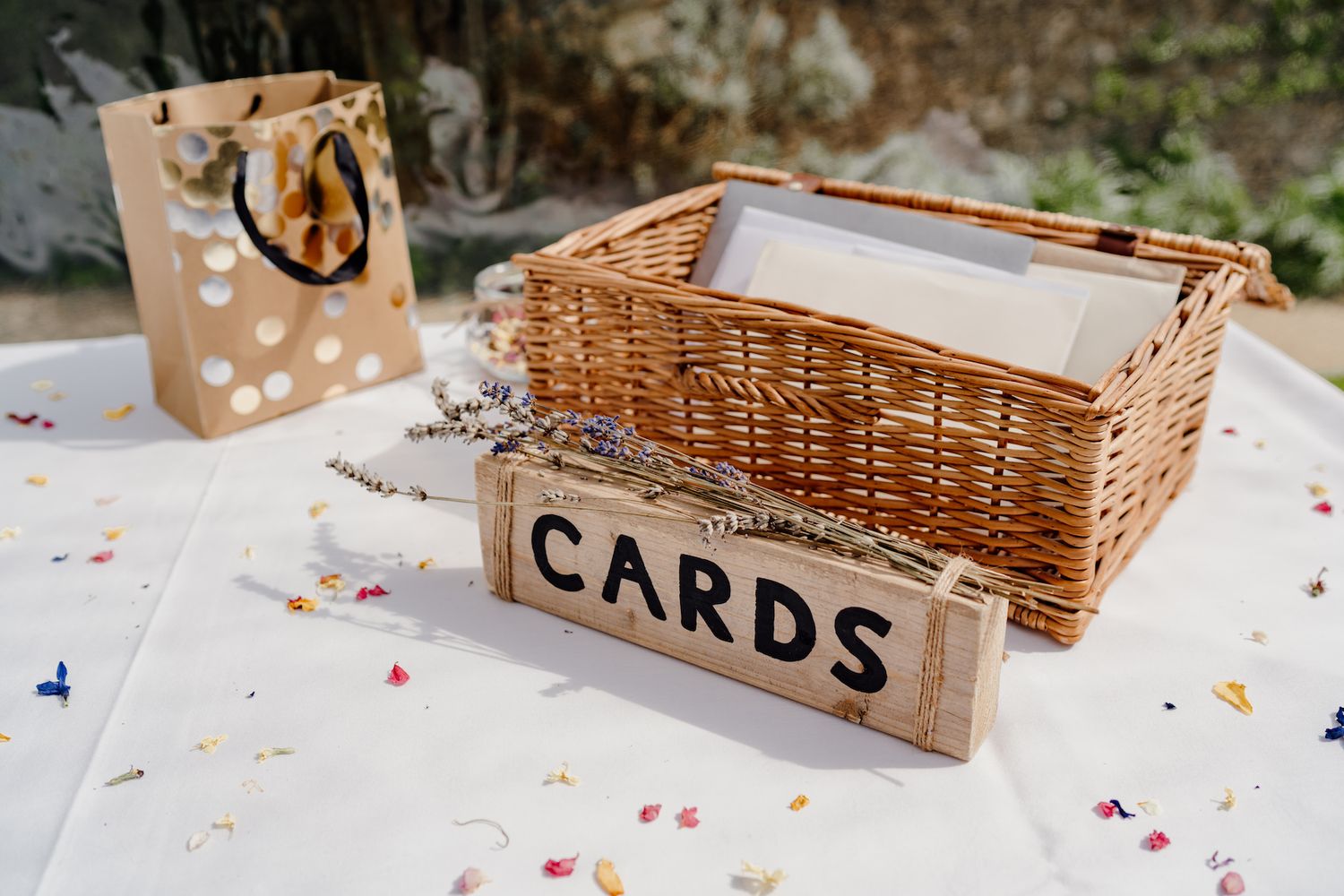 Wicker basket labeled 'Cards' sits on a white table with scattered colorful confetti.