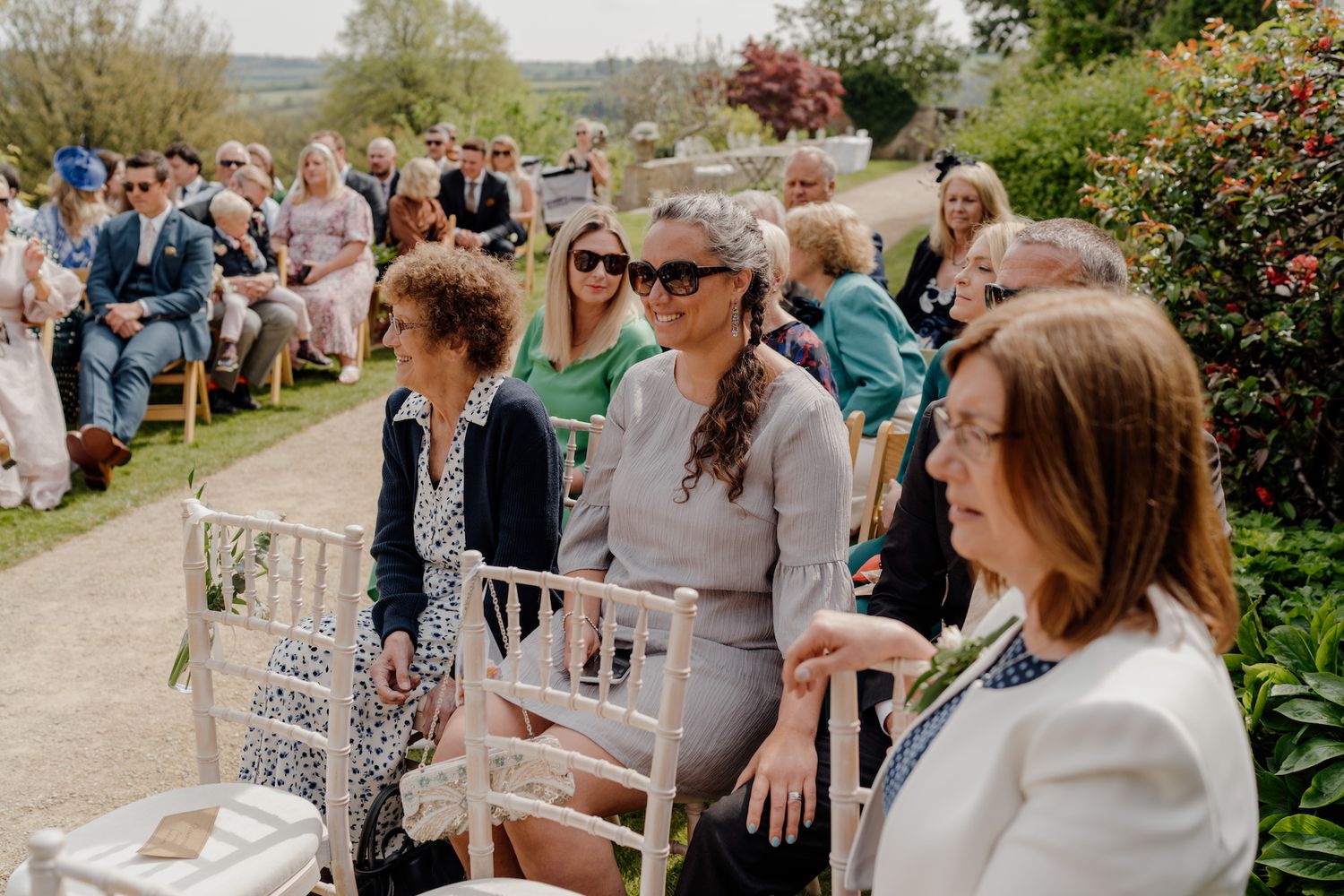 Outdoor wedding ceremony with guests seated in rows on a sunny day.