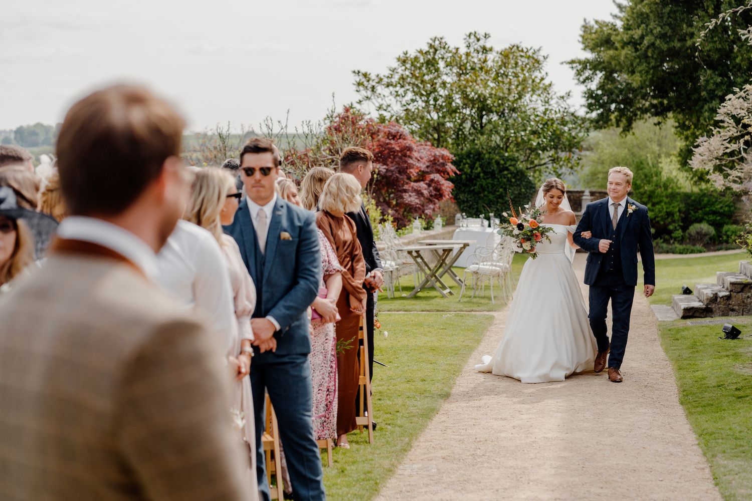 Wedding processional on garden path with guests lining the walkway.